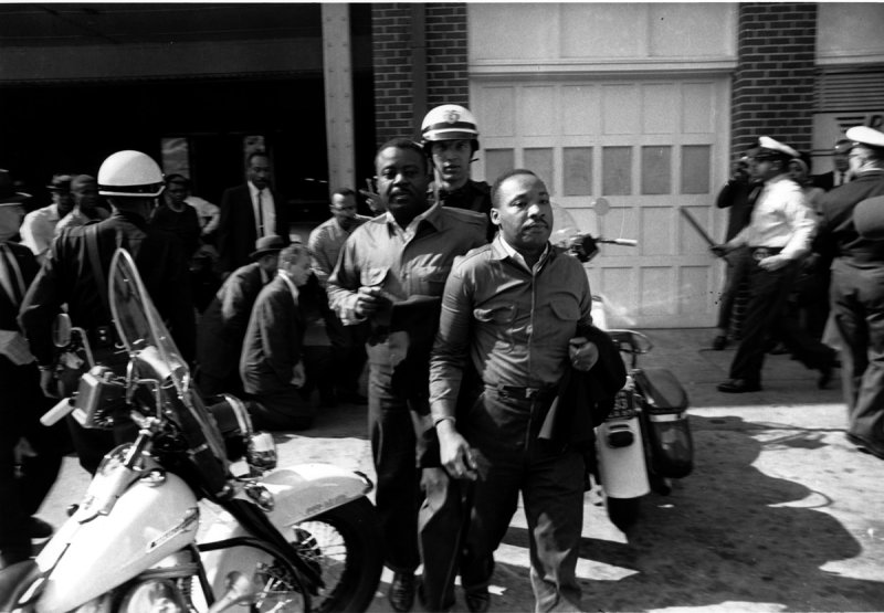 Dr. Martin Luther King Jr. being arrested during a nonviolent protest. A black-and-white photo showing the reality of civil disobedience in action.